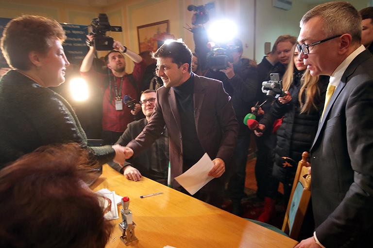 На фото: украинский комик и актер Владимир Зеленский (справа) пожимает руку сотруднику Центральной избирательной комиссии (ЦИК), во время представления документов для регистрации в качестве кандидата в президенты, Киев, 25 января 2019 года